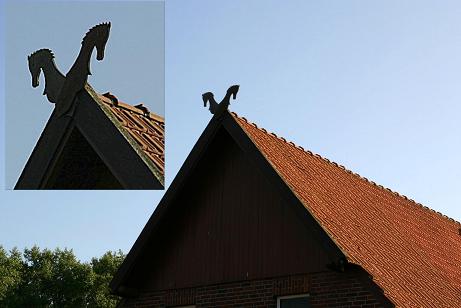 Hölzerner Pferdekopf als Giebelschmuck auf einem Ziegeldach, im Ausschnitt vergrößert
